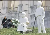  ?? AP PHOTO ?? Two women set flowers by a statue of Jacinta and Francisco Marto at the Fatima Sanctuary Thursday in Fatima, Portugal. Pope Francis is visiting the Fatima shrine this week to canonize the two Portuguese shepherd children whose “visions: of the Virgin...