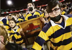  ?? Stephen Lam / The Chronicle ?? Left, members of the Cal Rally Committee celebrate with the Axe after the Big Game win. Right, Stanford wide receiver Elijah Higgins rushes upfield.