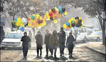  ?? AFP ?? Afghan balloon vendors walk past the ministry of public works a day after militants attacked it.