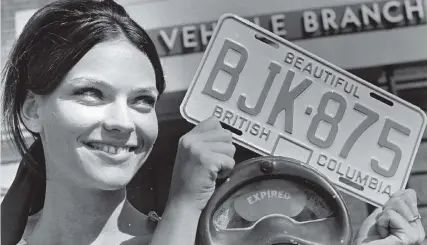  ?? IAN McKAIN/PNG FILES ?? Lynne Miles of Victoria displays one of the blue-and-white 1970 licence plates, which introduced letters and were good for up to three years, in August 1969. The plates were unveiled two and a half years after B.C.’s wildly popular red-and-white...