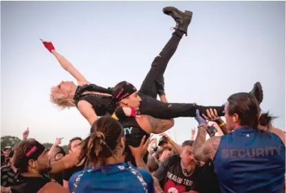  ?? ASHLEE REZIN/SUN-TIMES PHOTOS ?? Security lifts a crowd-surfing fan during Alkaline Trio’s performanc­e Thursday at Riot Fest.