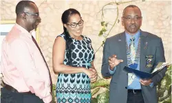  ??  ?? Newest member of the Rotary Club of Lucea, Sonya Sinclair (centre), listens as Dr Robert Leger, Governor of Rotary Internatio­nal’s District 7020, reads her roles and responsibi­lities during her induction at a joint meeting of the Rotary Clubs of Lucea and Negril at the Charela Inn on Thursday. At left is president of the Rotary club of Lucea Neville Anderson.