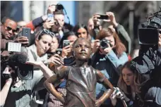  ?? MARK LENNIHAN, AP ?? People stop to photograph the Fearless Girl statue in New York. Visbal finished the statue over a feverish two months.