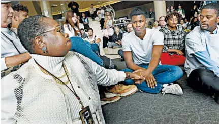  ?? JEAN PIERI/PIONEER PRESS ?? Assistant professor Aura Wharton-Beck, left, clasps hands with freshman Kevyn Perkins before a protest over a racial slur at the University of St. Thomas.