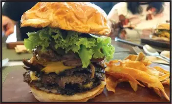  ??  ?? Ultimeat Burger. One heck of a stack! Made by Luis, it’s topped with bacon, pork adobo, caramelize­d onions, lettuce and jalapeño.