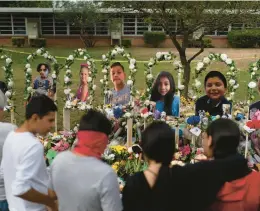  ?? JAE C. HONG/AP ?? People gather Monday at a memorial at Robb Elementary School in Uvalde, Texas, to pay their respects to the victims killed in last week’s school shooting.