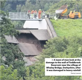  ?? Danny Lawson ?? > A team of men look at the damage to the wall of Toddbrook Reservoir near the village of Whaley Bridge, Derbyshire, after it was damaged in heavy rainfall