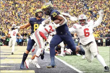  ?? Mike Mulholland / Getty Images ?? Michigan’s Hassan Haskins carries the ball into the end zone for a touchdown against Ohio State on Saturday.