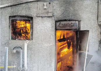  ?? PHOTOS: BRANDON HARDER ?? A look through the rear door at Lang’s Cafe early Wednesday morning reveals a mass of flames in the interior of the Regina restaurant. The blaze also caused damage to some nearby businesses.