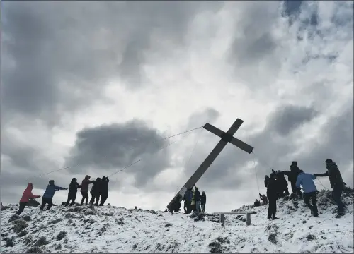  ?? PICTURE: BRUCE ROLLINSON. ?? SEASONAL RITUAL: Volunteers help to raise the Chevin Cross on its 50th anniversar­y after carrying the 36-foot wooden landmark up the hill .