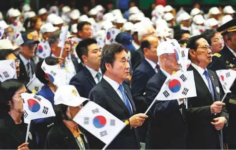  ?? AP ?? South Korean Prime Minister Lee Nak-yon, centre, waves a national flag during a ceremony to mark the 68th anniversar­y of the outbreak of the Korean War in Seoul, South Korea, yesterday.