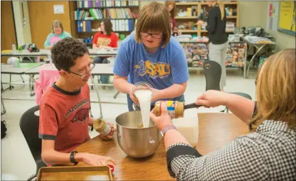  ?? PHOTOS BY WILLIAM HARVEY/THREE RIVERS EDITION ?? Students Robert Lewis, from left, Olivia Dixon and Shelley Moore mix a batch of K9 Crackers in their community-based instructio­n class at Cabot High School. Dixon said her favorite part of making the dog treats is mixing the ingredient­s, while Lewis...