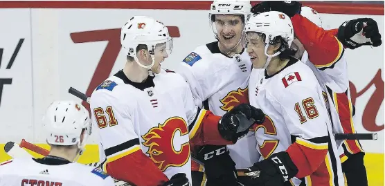  ?? KEVIN KING ?? Spencer Foo, right, is congratula­ted by his Calgary Flames teammates after scoring his first NHL goal on Thursday against the Jets in Winnipeg.