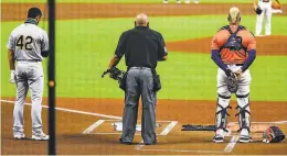  ?? Bob Levey / Getty Images ?? Marcus Semien of the A’s, umpire Adrian Johnson and the Astros’ Martin Maldonado stand for a moment of silence before both teams walked off.