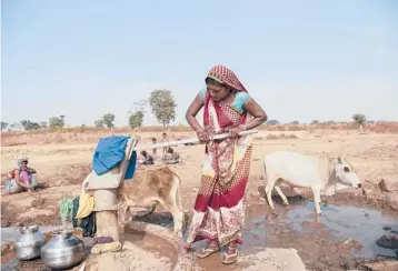  ?? SAUMYA KHANDELWAL/THE NEW YORK TIMES ?? A woman fills water containers in Imlidol, India, where water scarcity limits crops.