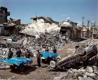  ?? Felipe Dana/Associated Press ?? Moradores da zona oeste de Mossul carregam corpos de civis mortos após ataque aéreo IRAQUE