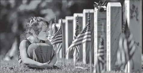  ?? AFP ?? A girl sits in the grass near the headstones of those killed during the wars in Iraq and Afghanista­n at a cemetery on May 31, 2021 in Arlington, Virginia, US.