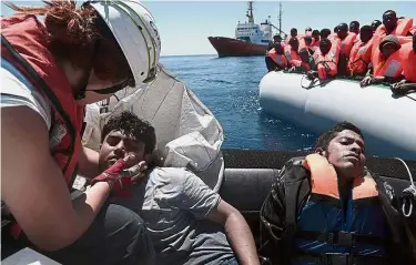  ?? — Reuters ?? Fortunate fate: A rescuer helping some of the migrants saved by the ‘Aquarius’ team in the central Mediterran­ean Sea.