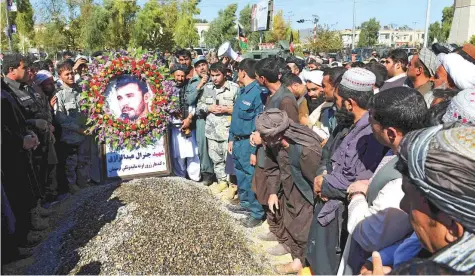  ?? AP ?? Civilians and military personnel stand beside the grave of General Abdul Raziq, Kandahar police chief, during his burial ceremony in Kandahar, yesterday. Afghanista­n’s election commission yesterday postponed elections in Kandahar for a week.