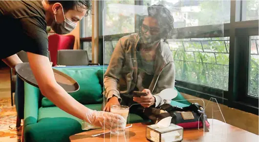  ?? SALMAN TOYIBI/JAWA POS ?? IKUTI PROTOKOL KESEHATAN: Kedai Kopi Mill Point di Depok, Jawa Barat, memasang sekat plastik di meja untuk mencegah penularan virus korona.
