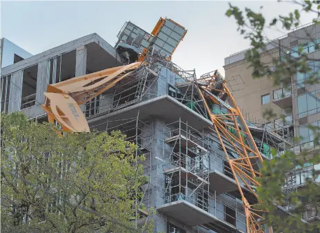  ?? CP PHOTOS ?? Above, A toppled building crane is draped over a new constructi­on project in Halifax on Sunday. Right, members of the 4 Engineer Support Regiment from Camp Gagetown assist in the cleanup in Halifax on Monday.