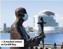  ??  ?? > A masked statue at Cardiff Bay