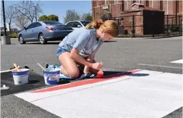  ?? Ruby Larson/appeal-democrat ?? Senior Corrine Mathews paints her parking space at Marysville High School on Thursday.