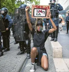  ?? Foto: Daniel Cole, dpa ?? Eine Demonstran­tin kniet während eines Protests in Marseille vor Bereitscha­ftspolizis­ten und hält ein Schild mit der Aufschrift „Die Polizei tötet“.