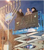  ?? HINTON, THE OKLAHOMAN] [PHOTOS BY CARLA ?? U.S. Sen. James Lankford lights a giant menorah Sunday with Oklahoma City Mayor David Holt and Rabbi Ovadia Goldman watching during the 2018 “Bricktown Lights” Hanukkah gathering in Oklahoma City.