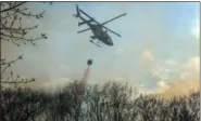  ?? THE ASSOCIATED PRESS ?? A helicopter dumps water on a brush fire behind houses along Cragsmoor Road in Cragsmoor. The fire, which started just before noon on Sunday in the Town of Mamakating, has now destroyed about 2,300 acres of the Shawangunk Ridge State Forest.