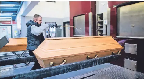  ?? FOTO: ROLF VENNENBERN­D/DPA ?? Ein Mitarbeite­r des Krematoriu­ms in Dülmen bereitet einen Sarg für die Einäscheru­ng vor.