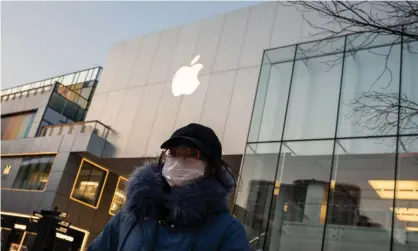  ??  ?? A woman wearing a protective face mask walks outside a closed Apple Store in Beijing. Photograph: Nicolas Asfouri/AFP via Getty Images