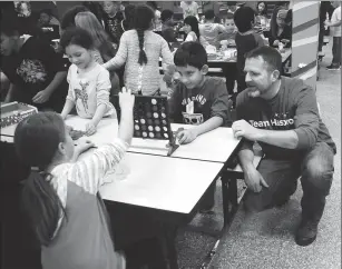  ?? Ernest A. Brown/The Call ?? Hasbro employee Eric Huban, right, watches as Kevin Coleman Elementary School students Serenity Delorme, left, and Adam Mohamed, enjoy a game of Connect Four as Hasbro representa­tives stopped by the school to distribute toys and games as part of...