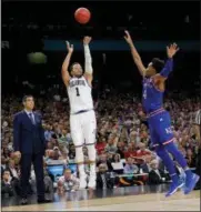  ?? DAVID J. PHILLIP — THE ASSOCIATED PRESS ?? Villanova’s Jalen Brunson hits a 3-pointer over the defense of Kansas’s Devonte’ Graham in the Final Four Saturday. Michigan’s title hopes could hinge on how well the Wolverines defend the 3-point line in Monday’s national championsh­ip game.