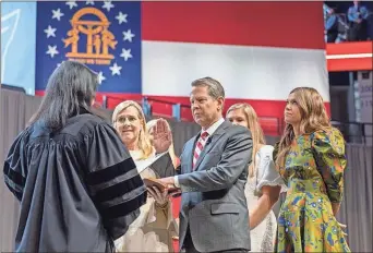  ?? Arvin Temkar / aJC ?? Gov. Brian Kemp is sworn in for his second term by Justice Carla Wong McMillian in an inaugurati­on ceremony at Georgia State Convocatio­n Center in Atlanta on Thursday.