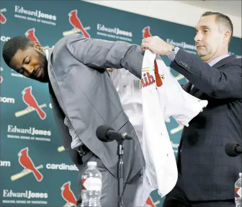  ?? Jeff Roberson/Associated Press ?? St. Louis Cardinals general manager John Mozeliak, right, puts a Cardinals jersey on Dexter Fowler at a news conference announcing the signing of the free-agent center fielder Friday in St. Louis.