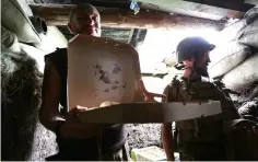  ??  ?? Ukrainian servicemen who fight against Russian-backed separatist­s hold a box with pizza delivered to the frontline by Kachko.