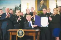  ?? AL DRAGO / THE NEW YORK TIMES ?? President Donald Trump displays a bill he signed into law June 2 at the White House. Today marks Trump’s sixth month in office, and despite his braggadoci­o of signing bills into law at a record-setting pace, he is only slightly ahead of the average...