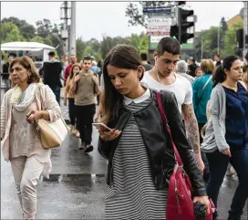  ?? BORYANA DIMITROVA KATSAROVA / THE NEW YORK TIMES ?? A woman checks her mobile phone in Sofia, Bulgaria, earlier this month. As of Thursday there will be no more extra fees for using an EU handset in another EU country; roaming charges can add hundreds of euros to a vacation bill.