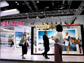  ?? AP/ANDY WONG ?? Visitors pass a Foxconn exhibit promoting its Sharp 8K flat screen TV in Beijing on Sept. 7.