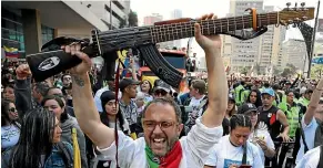  ?? AP ?? Colombian musician Cesar Lopez holds up his ‘‘escopetarr­a,’’ a guitar that incorporat­es an assault rifle as a symbol of peace, during a musical protest against the government of President Ivan Duque in Bogota earlier this month.