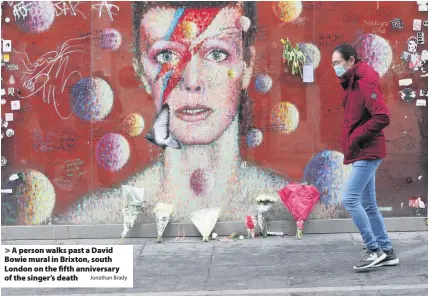  ?? Jonathan Brady ?? > A person walks past a David Bowie mural in Brixton, south London on the fifth anniversar­y of the singer’s death