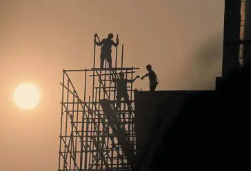  ?? — AFP ?? Special focus: Workers are seen on scaffoldin­g at a constructi­on site in Beijing. The implementa­tion of key projects will give a strong impetus to China’s economic and social developmen­t.