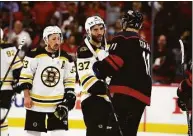  ?? Karl B DeBlaker / Associated Press ?? The Bruins' Patrice Bergeron (37) shakes hands with the Hurricanes' Jaccob Slavin, with Brad Marchand (63) nearby after Game 7 of their Stanley Cup first-round playoff series Saturday.