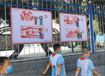  ?? Photograph­s by Alice Su Los Angeles Times ?? SCHOOLCHIL­DREN pass patriotism signs at an elementary school in Hohhot. China has announced that students in its Inner Mongolia region would be transition­ing from Mongolian to Mandarin in half their classes.