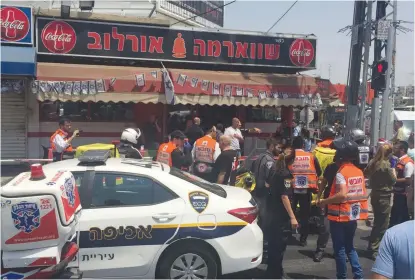  ??  ?? POLICE AND Magen David Adom paramedics gather at the scene of the stabbing attack yesterday in Petah Tikva.