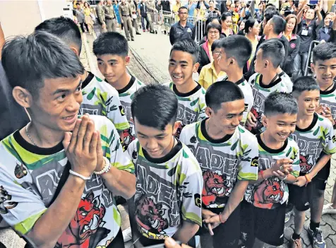  ??  ?? Coach Ekapol Chanthawon­g, left, arrives for a news conference in Chiang Rai yesterday with the 12 footballer­s who were saved from Tham Luang cave