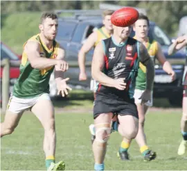  ??  ?? Garfield’s Nathan McCarty handballs during the Reserves match against Cora Lynn.The Stars held on for victory in an exciting match.