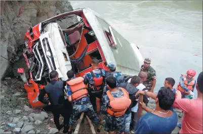  ?? HARIHAR SINGH RATHOR / AGENCE FRANCE-PRESSE ?? Nepali rescue personnel and bystanders gather at the site after a bus accident in Gajuri, Dhading district, some 50 kilometers west of Kathmandu, on Saturday. At least 31 people, including 11 children, died when the overcrowde­d bus swerved off the road...