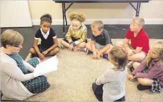  ?? CONTRIBUTE­D ?? Teacher Katie Pearce reads to a first- and second-grade class at the Veritas Classical Schools. The hybrid school brings students together twice a week while promoting independen­t home study.